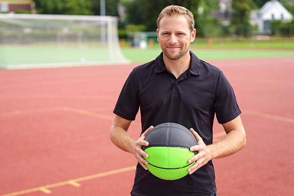 Sportlich begeisterter Unternehmer mit Basketball in den Händen auf dem Sportplatz