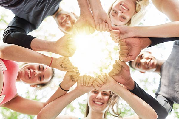 Fünf junge Menschen bilden mit den Händen eine Geste des Zusammenhalts