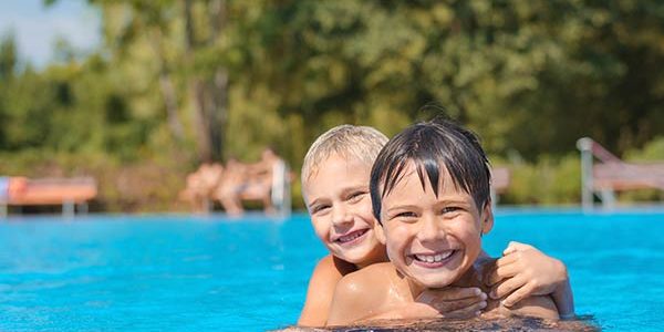 Zwei Kinder am Schwimmbad-Beckenrand